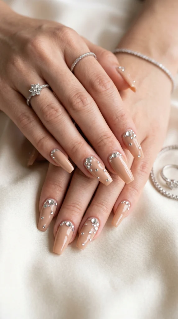  Coffin nails in warm nude beige with scattered diamond rhinestones of varying sizes for quiet luxury sparkle