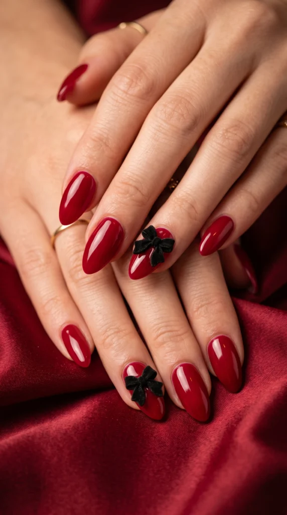 Almond nails in cherry red glossy with black velvet bow charm accent for coquette soft girl aesthetic