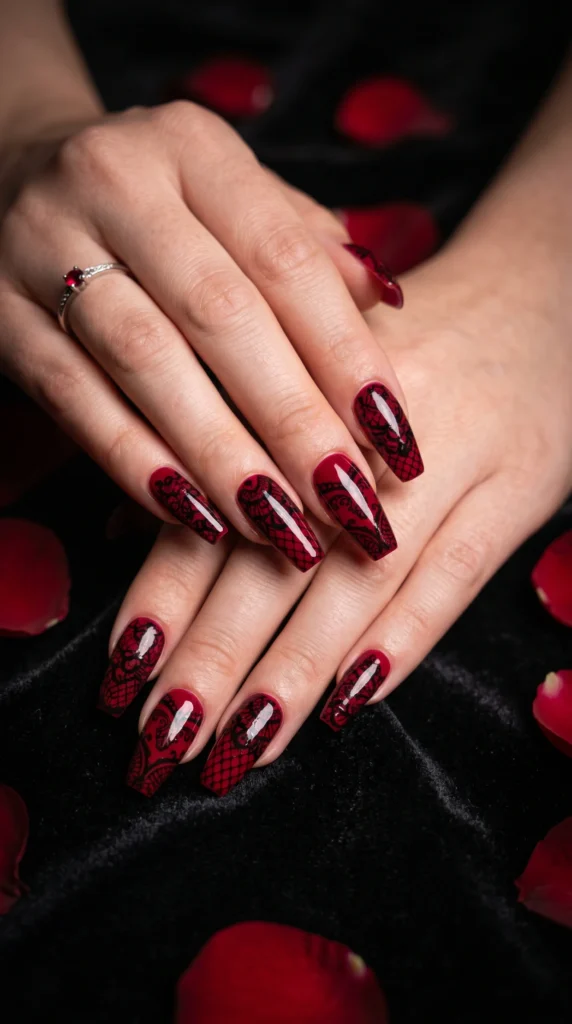 Coffin nails in crimson red with intricate black lace overlay pattern across all nails dramatic stunning look