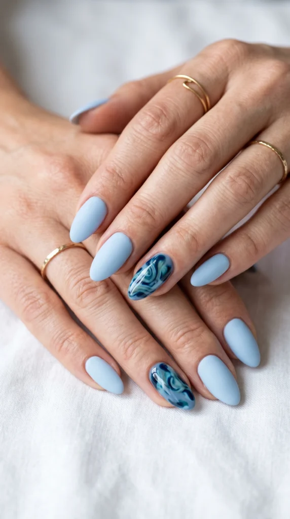 Almond nails in matte baby blue with hand-painted blue tortoiseshell swirl accent nail, cool modern style