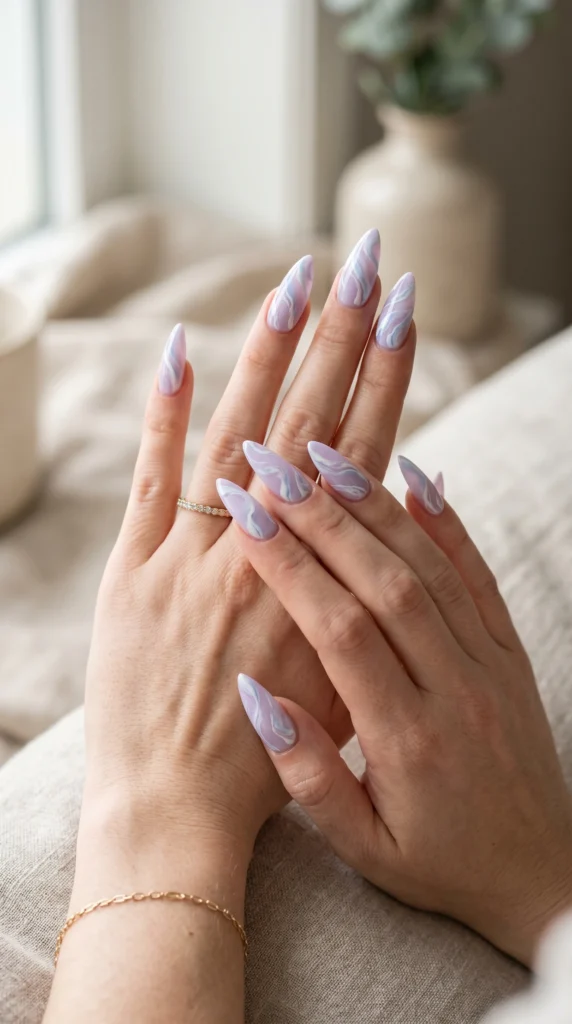Long stiletto nails in pastel lilac with flowing white and blue abstract swirl art, artistic soft girl nail design
