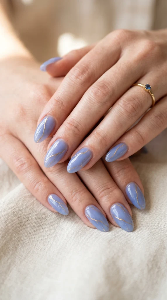 Almond periwinkle blue jelly nails with fine hand-painted gold vein lines — oceanic translucent art
