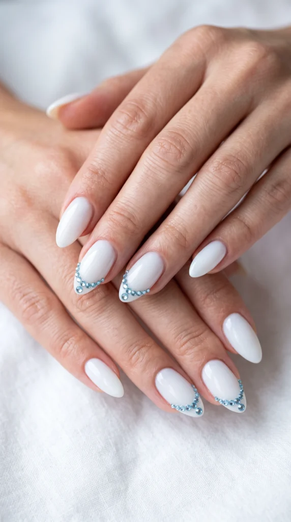 A person's hand with white nail polish and blue glitter.