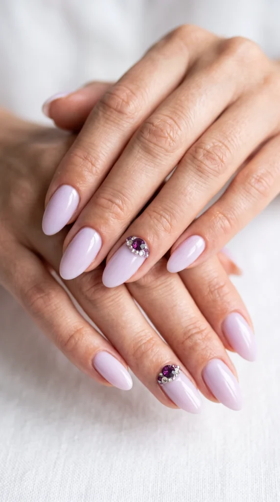A person's hands with purple nail polish and a purple stone on the middle finger.
