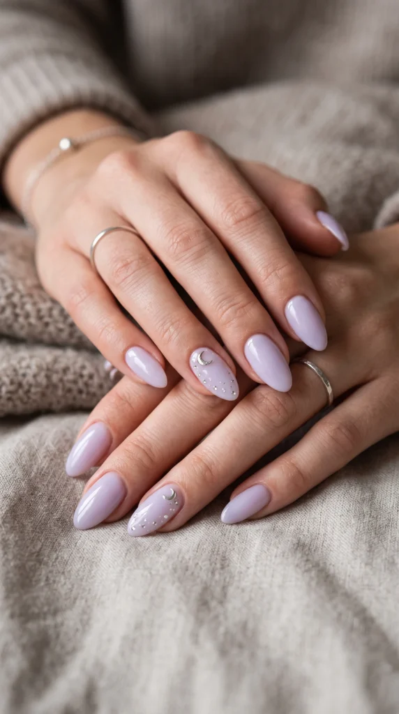 Almond nails in milky lavender with silver moon charm and rhinestone star accent, celestial feminine style