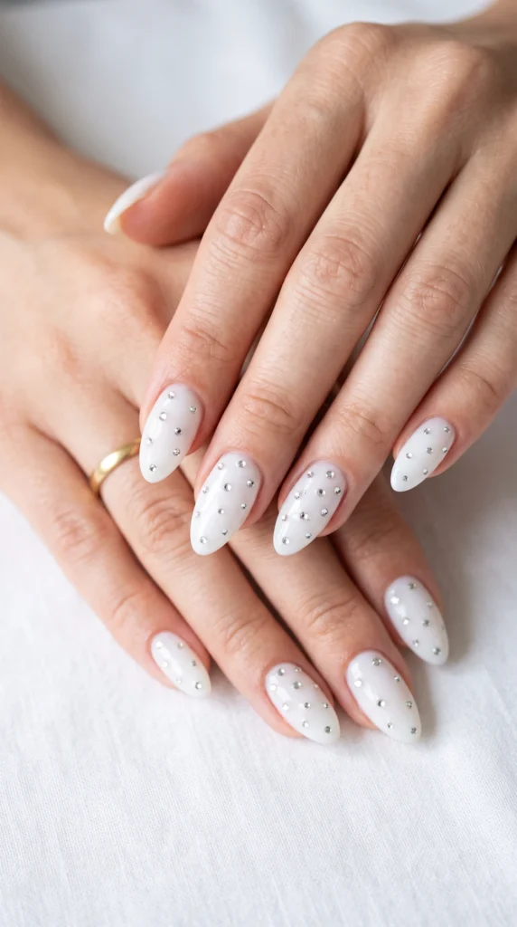 A woman with white nail polish and white dots on her fingernails.