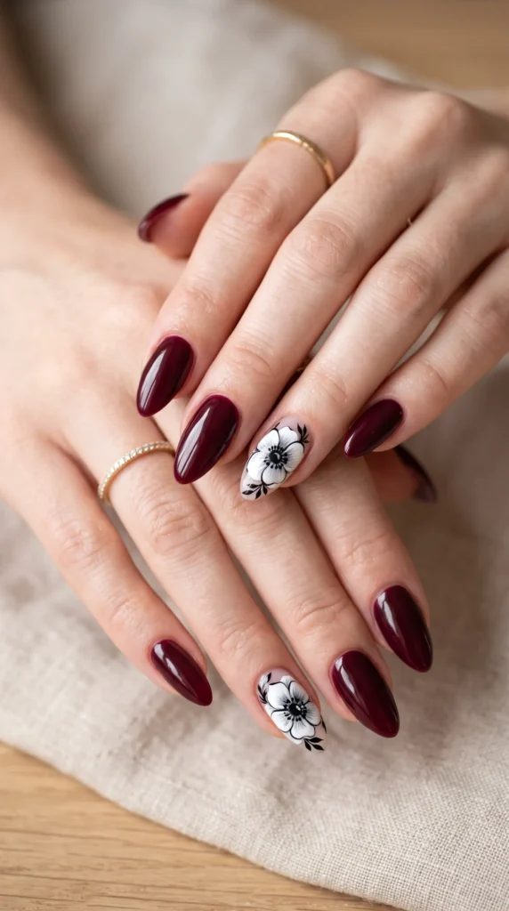 A woman with red nail polish and a white flower design on her fingernails.