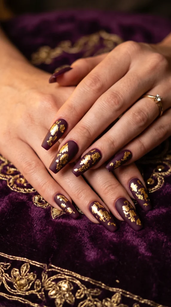 A woman with purple nail polish and gold accents on her nails.