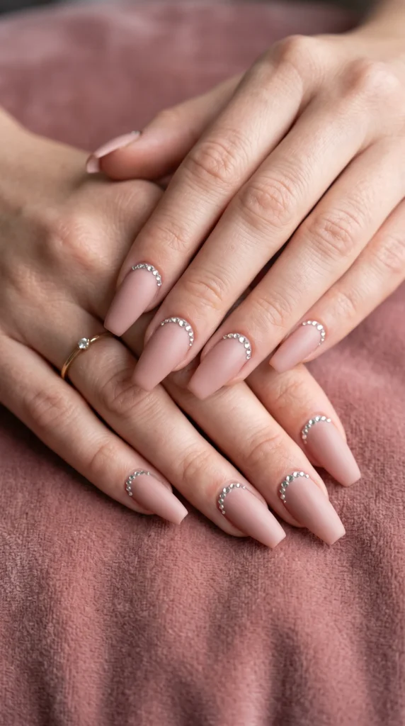 A woman's hands with pink nail polish and rhinestones.