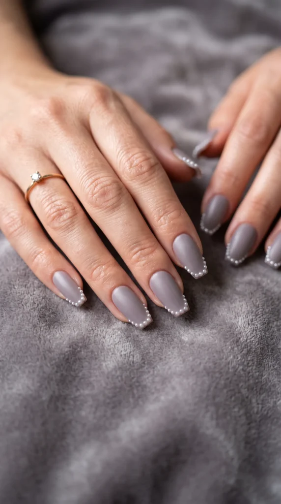 A woman's hand with a ring on her finger and a grey nail polish.