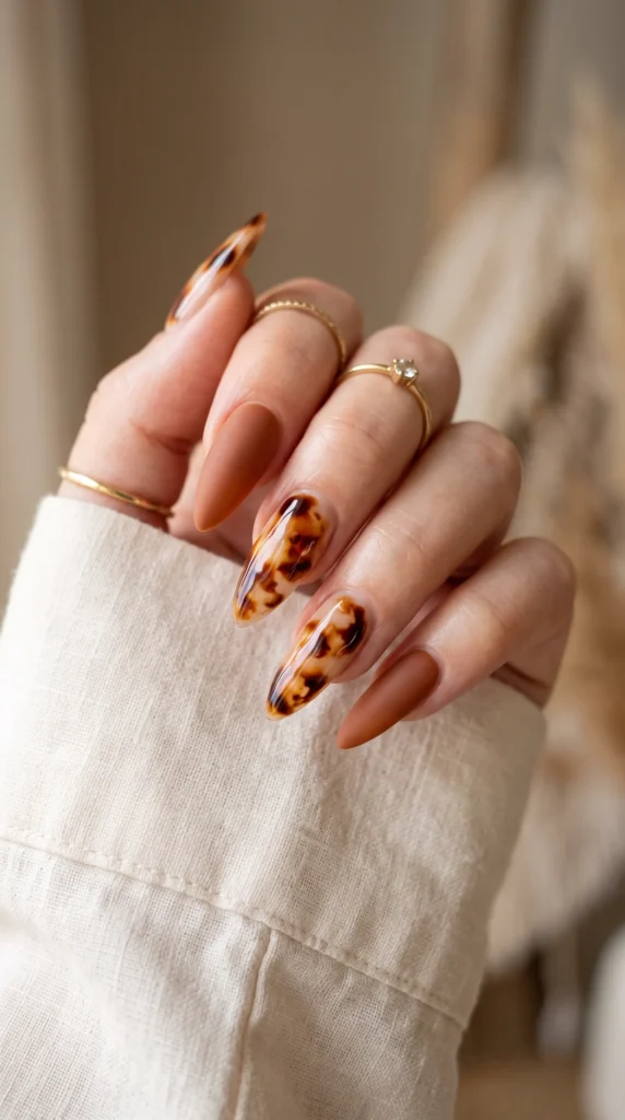 A woman with a gold ring on her finger is holding her hand with a leopard print nail polish.