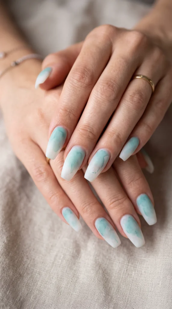 A person's hand with blue and white nail polish.