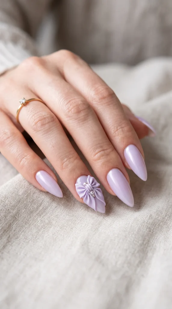A woman with a ring on her finger has purple nail polish and a purple bow on her nails.