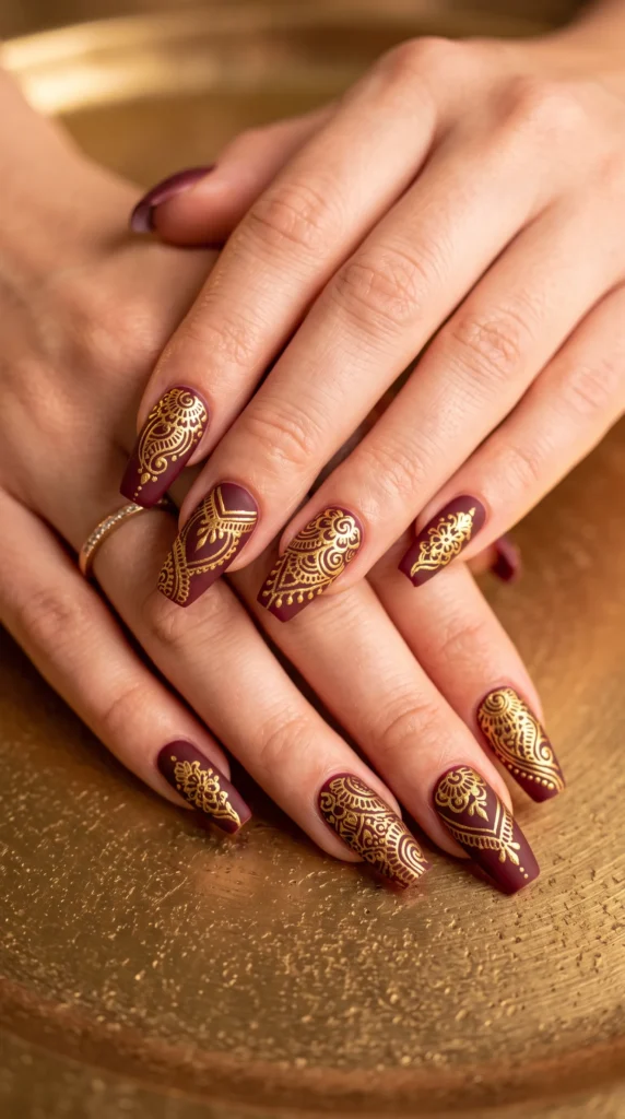 A woman's hands with gold and maroon nail polish.