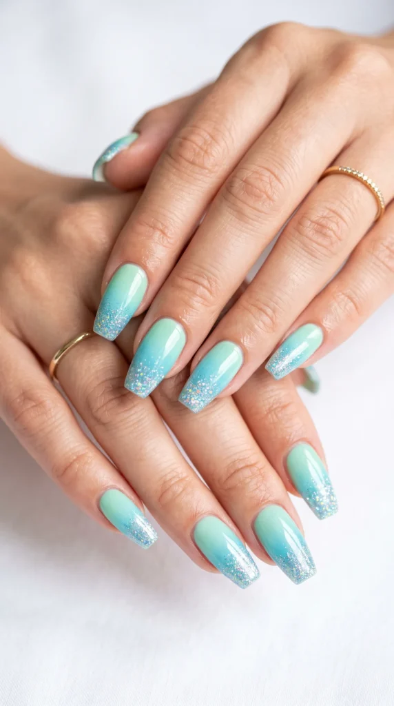 A person's hand with blue and green nail polish.