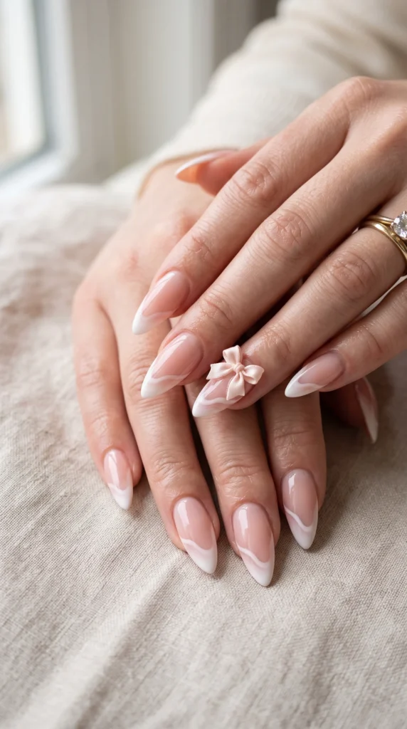 A person's hand with a pink nail polish and a bow on the nail.