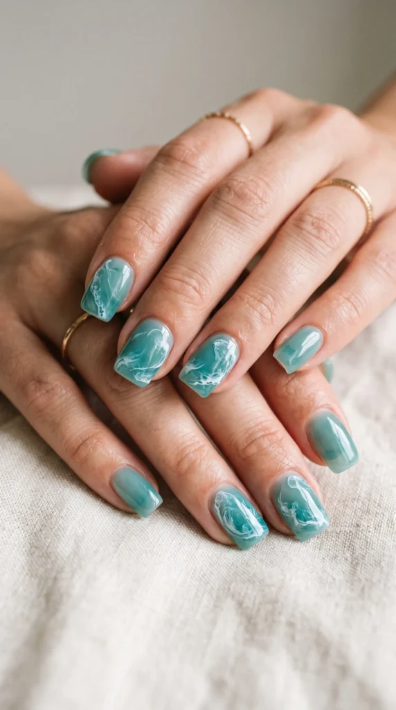 A person's hand with blue nail polish and a ring on the finger.
