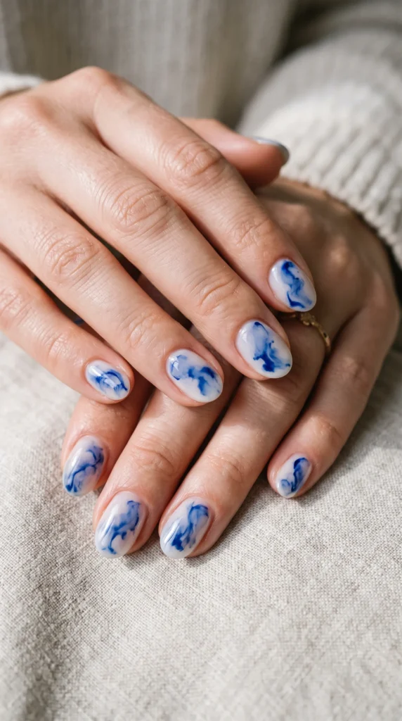A person with blue and white nail polish on their fingernails.