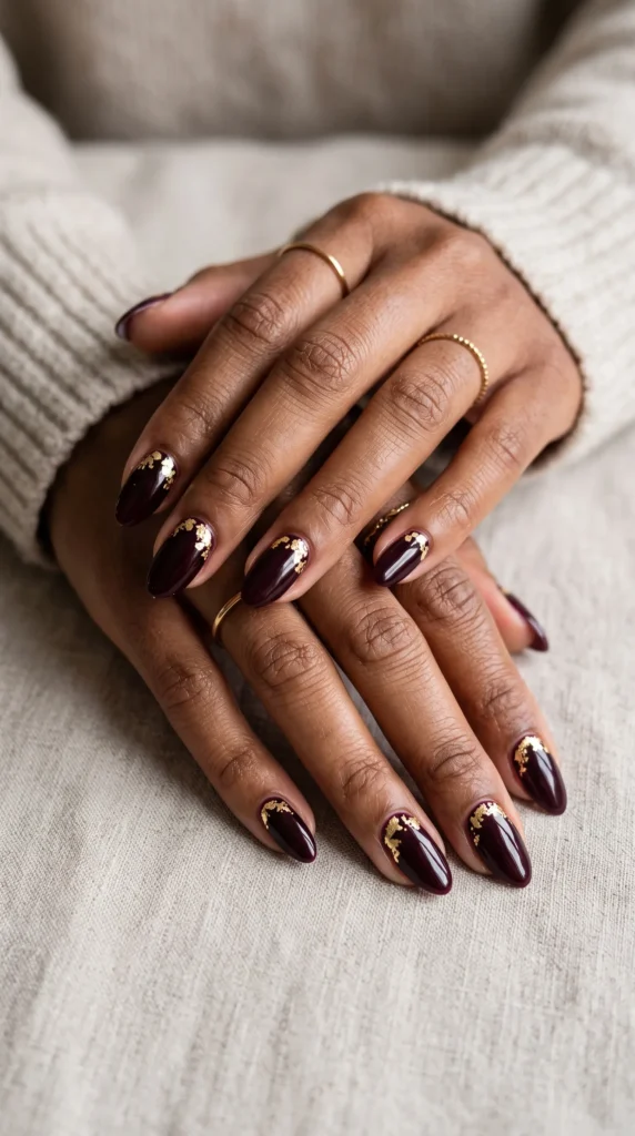 A woman with red nails and gold accents on her nails.